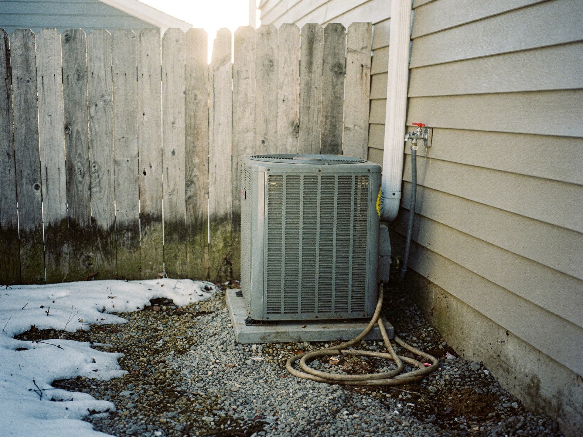 An outdoor condenser on a mulch bed beside a Derry subdivision colonial.