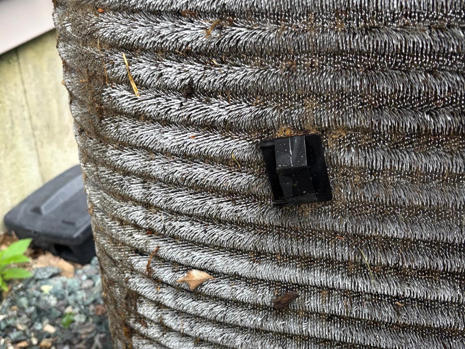 Outdoor condenser coil packed with grass, dirt and debris between the fins before cleaning
